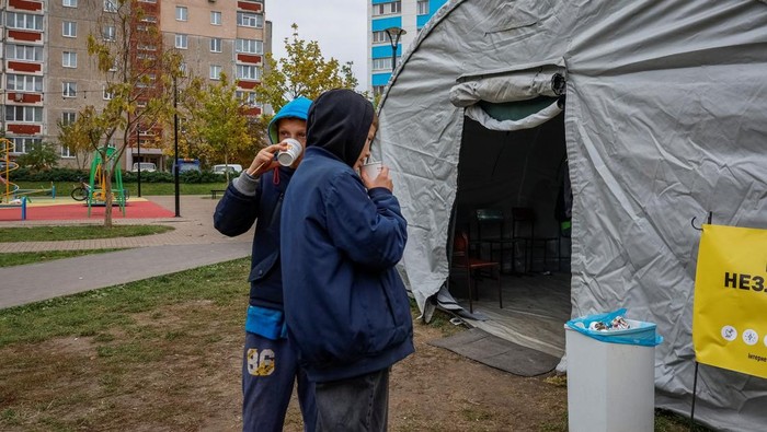 Boys drink tea next to an invincibility centre, where people can use Internet connection, charge their devices and warm up, amid water and electricity supply outage, after critical infrastructure was hit during a Russian drone attack, in Chernihiv, Ukraine October 21, 2025. REUTERS/Alina Smutko