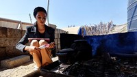 Mhanna menyiapkan makanan di luar tendanya di Deir al-Balah. Mhanna memperoleh nilai 85 persen dalam ujiannya dan lulus sekolah. Sebagian besar wilayah enklave tersebut, yang menderita kemiskinan dan pengangguran yang tinggi bahkan sebelum perang, telah dihancurkan, termasuk lembaga-lembaga pendidikannya. REUTERS/Mahmoud Issa