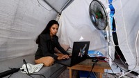 Siswi Palestina Raghad Loai Mhanna, yang lulus ujian SMA saat tinggal di tenda setelah mengungsi selama perang, bekerja di laptopnya di dalam tendanya di Deir al-Balah, Jalur Gaza tengah. Jalan menuju kelulusan itu panjang dan penuh tantangan. Mhanna menghadapi perang, kurangnya akses terhadap kebutuhan dasar, dan mengasuh keempat adik perempuannya, semuanya sambil terpisah dari ibunya. REUTERS/Mahmoud Issa