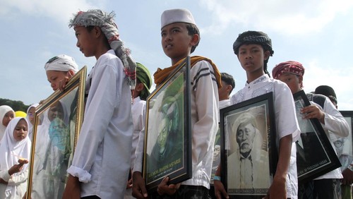 Santri membawa foto sejumlah kyai saat mengikuti gerak jalan dalam Festival 1001 Terompah di Lapangan Tumapel, Singosari, Malang, Jawa Timur, Rabu (22/10/2025). Festival yang digelar untuk memeriahkan Hari Santri Nasional 2025 itu juga diisi dengan gerak jalan berterompah sebagai simbol kesederhanaan dan penguatan nilai-nilai keislaman di kalangan santri. ANTARA FOTO/Ari Bowo Sucipto