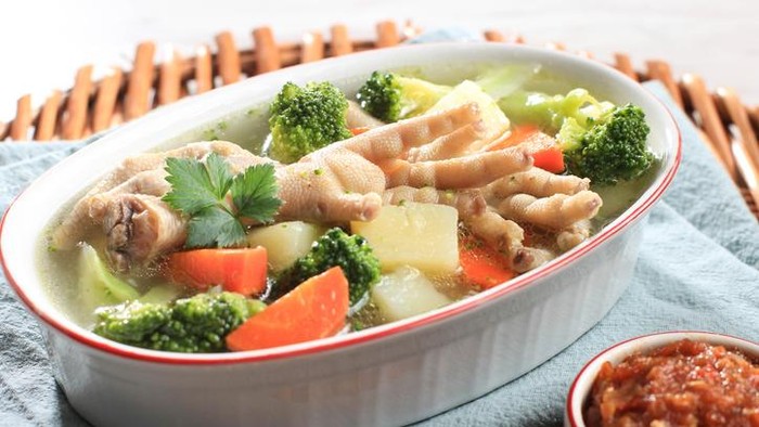 Clear Chicken Feet (Claw) Soup with Potato, Broccoli, and Carrots. Served on Marble Table in Brown Bowl with Sambal