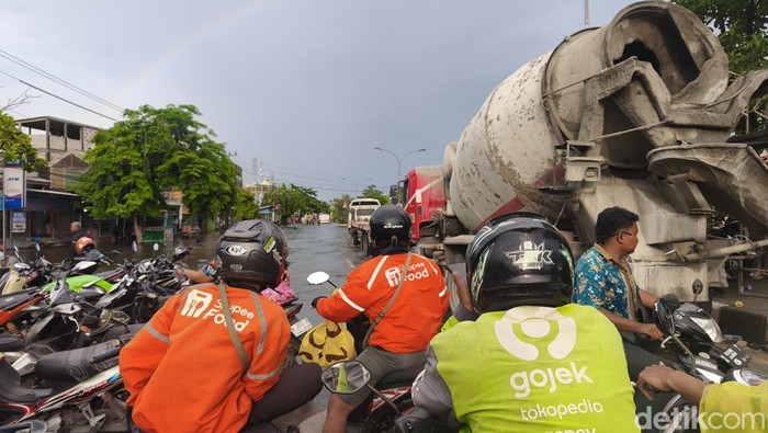 Driver ojol sedang menunggu pelanggan di bibir banjir Jalan Kaligawe Raya, Kecamatan Gayamsari, Kota Semarang, Kamis (23/10/2025). Driver ojol sedang menunggu pelanggan di bibir banjir Jalan Kaligawe Raya, Kecamatan Gayamsari, Kota Semarang, Kamis (23/10/2025).