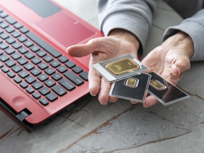 Senior woman using laptop and buying gold bar from home.Financial concept.