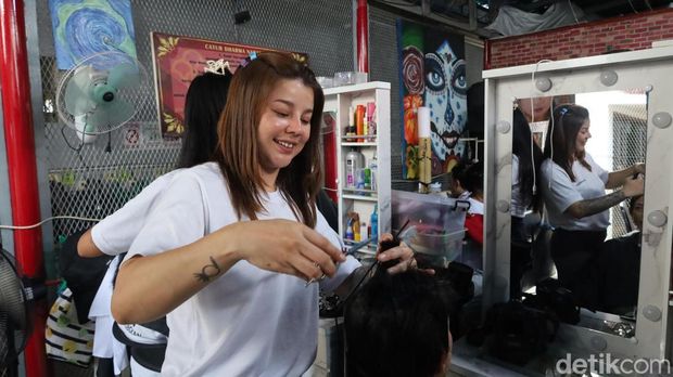 Kasarin saat sedang mengerjakan rambut salah seorang pelanggan di area dalam LPP Kerobokan, Rabu (22/10/2025). (Aryo Mahendro/detikBali).