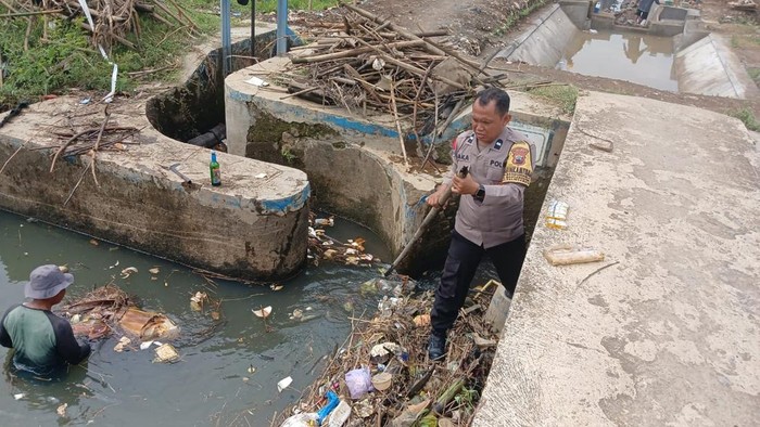 Bhabinkamtibmas Polsek Kalinyamatan, Aipda Jaka Priyana, bekerja bakti bersama warga membersihkan sungai Kaweden di Desa Manyargading, Kamis (23/10/2025).
