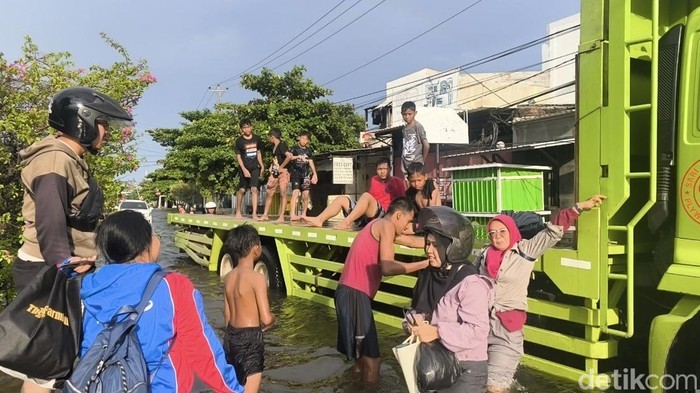 Masyarakat nebeng truk tronton untuk melintasi banjir, Kamis (23/10/2025).
