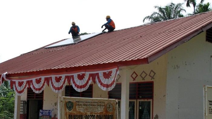Petugas PLN saat melakukan perawatan perangkat panel di atap sekolah. (Kartika Sari/detikSumut)