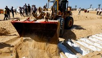 Alat berat membantu penguburan jenazah warga Palestina tak dikenal yang ditahan di Israel selama perang, setelah mereka diserahkan oleh Israel, di tengah gencatan senjata. Seorang juru bicara pemerintah Israel mengatakan bahwa Israel mematuhi hukum internasional dan laporan penyiksaan serta penganiayaan terhadap warga Palestina tersebut merupakan upaya lebih lanjut untuk menjelek-jelekkan Israel. REUTERS/Mahmoud Issa