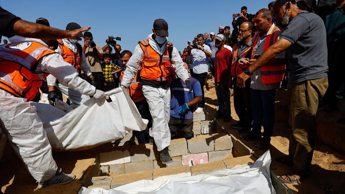 Pilu Warga Gaza Makamkan Puluhan Jenazah Tak Dikenal yang Diserahkan Israel People bury at a mass burial site unidentified bodies of Palestinians who had been held in Israel during the war, after they were handed over by Israel, amid a ceasefire between Israel and Hamas in Gaza, in Deir Al-Balah, in the central Gaza Strip, October 22, 2025. REUTERS/Mahmoud Issa
