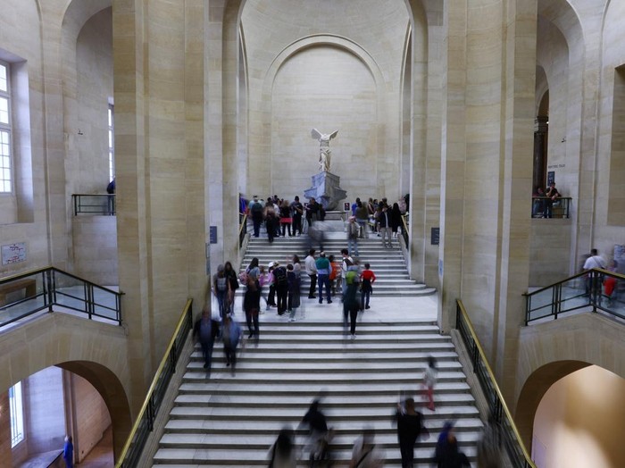 Visitors walk past the Victoire de Samothrace (The Winged Victory of Samothrace) marble statue displayed at the top of the Daru staircase at the Louvre Museum on the day it reopened to the public for the first time since last Sundays heist, while the Galerie dApollon where eight pieces of Napoleon and the Empresss jewelry collection displayed in the gallery were stolen by thieves, remains closed, in Paris, France, October 22, 2025. REUTERS/Gonzalo Fuentes