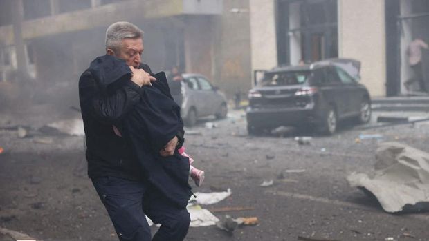 Seorang pria mengevakuasi anak dari taman kanak-kanak yang terkena serangan pesawat tak berawak Rusia, di tengah serangan Rusia terhadap Ukraina, di Kharkiv, Ukraina, 22 Oktober 2025. (Press service of the State Emergency Service of Ukraine/Handout via REUTERS)