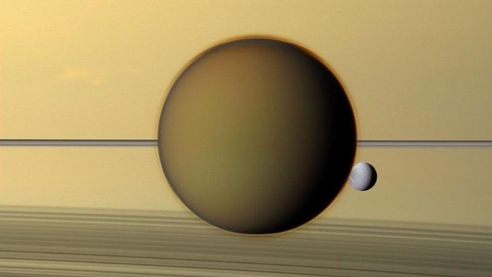 Titan Saturnus Titan (tengah), dan sesama bulan Dione (kanan), melintas di depan Saturnus dan cincinnya (latar belakang).