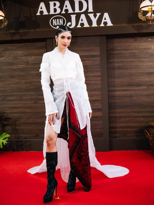 Mikha Tambayong mengenakan kebaya modifikasi karya desainer Wilsen Willim berwarna putih. Atasan dipadukan rok asimetris merah. Foto: Instagram/@evacelia @miktambayong