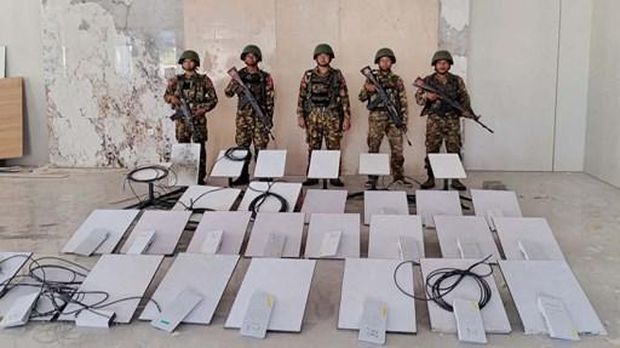 FILES-THAILAND-MYANMAR-SCAM-INTERNET-CRIME This handout photo taken on October 20, 2025 and released on October 22, 2025 by the Myanmar Military Information Team shows members of Myanmar's military standing next to Starlink devices seized during a raid on the KK Park online scam centre in Myawaddy, Myanmar's Kayin State. SpaceX has cut service to more than 2,500 Starlink devices at Myanmar scam centres, a company executive said October 22, after AFP revealed that their use had exploded in the illicit industry. Myanmar's military earlier on October 20 announced it had raided the KK Park scam centre and seized 30 Starlink satellite internet terminals.Handout / MYANMAR MILITARY INFORMATION TEAM / AFP