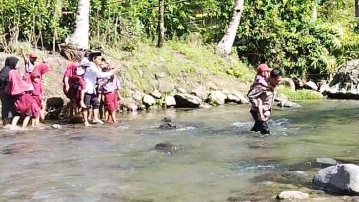 Polisi dan guru di Mamasa bertaruh nyawa menggendong siswa SD menyeberangi sungai.