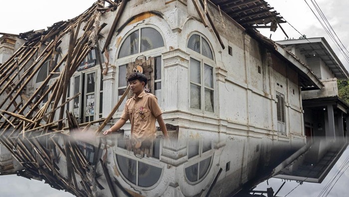 Pelajar berjalan di samping rumah berstatus objek diduga cagar budaya (ODCB) yang ambruk di Kampung Sukamaju, Batujajar, Kabupaten Bandung Barat, Jawa Barat, Jumat (24/10/2025). Rumah berarsitektur kolonial art deco yang berdiri sejak tahun 1850 dan sempat menjadi tempat berkumpul para pejuang pada masa revolusi fisik pasca proklamasi 1945 tersebut ambruk pada Kamis (23/10) akibat konstruksi bangunan serta atap yang lapuk. ANTARA FOTO/Abdan Syakura