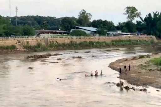 THAILAND-MYANMAR-SCAM-INTERNET-CRIME This screengrab from Thai PBS video footage taken in Mae Sot on October 22, 2025 and received by AFPTV on October 23, 2025 shows people crossing a section of the Moei river near KK Park in Myanmar (R) to Thailand. More than 600 people fled one of Myanmar's most notorious scam centres and crossed into Thailand, a Thai provincial official told AFP on October 23, after a military raid on the compound. Sawanit Suriyakul Na Ayutthaya, deputy governor of Tak province on the Myanmar border, told AFP