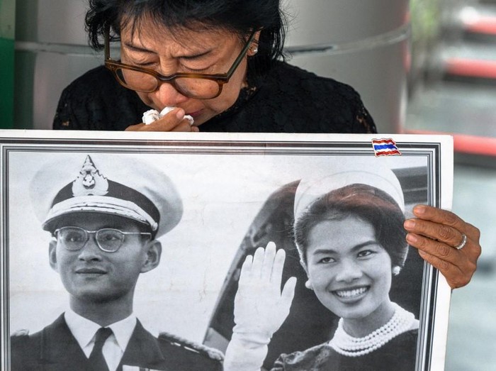 Salah satu pelayat tak kuasa menahan air mata saat memberikan penghormatan terakhir untuk Ibu Suri Sirikit di Rumah Sakit Chulalongkorn, Bangkok Thai mourner Kanjana Malaithong holds a portrait of Thailands former queen Sirikit and Thai King Bhumibol Adulyadej as she weeps at Chulalongkorn Hospital in Bangkok on October 25, 2025. Thailands former Queen Sirikit, the mother of the current King Vajiralongkorn and wife of the nations longest-reigning monarch, died late on October 24 at the age of 93, the palace said. (Photo by Chanakarn Laosarakham / AFP)
