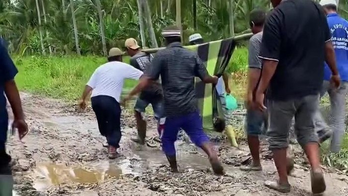 Warga di Kabupaten Asahan menggotong jenazah karena jalan rusak parah (Dok. Media sosial) Warga di Kabupaten Asahan menggotong jenazah karena jalan rusak parah (Dok. Media sosial)
