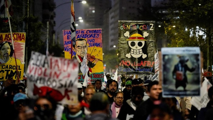 Aksi Warga Peru Protes Lonjakan Kejahatan dan Kekerasan Polisi Demonstrators hold up signs as they take part in a protest against rising crime, economic instability, and government corruption, in Lima, Peru, October 25, 2025. REUTERS/Angela Ponce