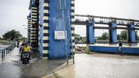 Pengendara sepeda motor melintasi jembatan di Bendungan Wilalung. Debit air tertinggi tercatat mencapai 800 meter kubik per detik sehingga telah melebihi ambang batas dalam standar operasional prosedur. Foto: ANTARA FOTO/Aprillio Akbar