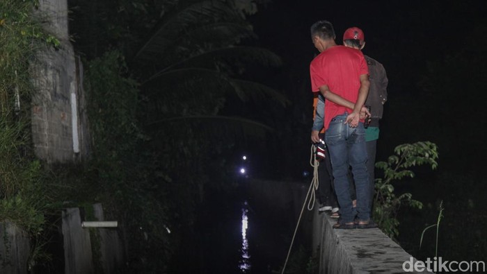 Petugas BPBD Tangsel menyisir aliran kanal di perumahan Pamulang Indah, Tangsel, Minggu (26/10/2025). Seorang bocah berinisial A dilaporkan hanyut terseret arus.