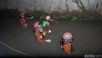 Petugas BPBD Tangsel menyisir aliran kanal di perumahan Pamulang Indah, Tangsel, Minggu (26/10/2025). Seorang bocah berinisial A dilaporkan hanyut terseret arus.