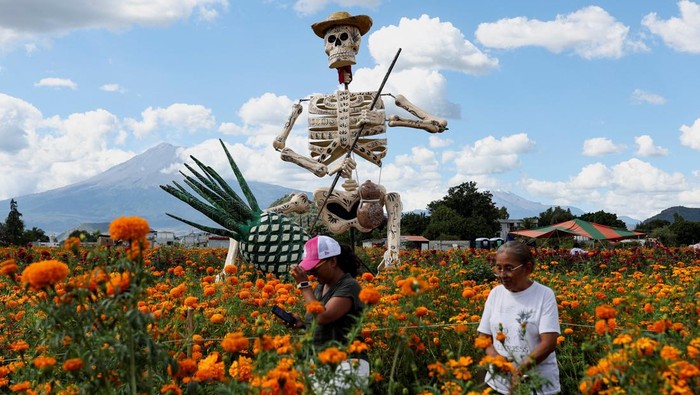 Kerangka Raksasa Hiasi Perayaan Hari Orang Mati People walk past a giant skeleton figure called