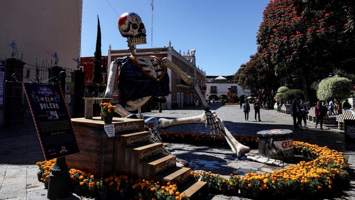 Kerangka Raksasa Hiasi Perayaan Hari Orang Mati People walk past a giant skeleton figure called