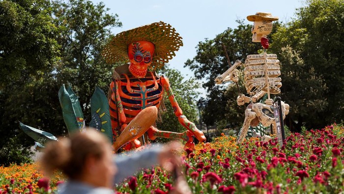 Kerangka Raksasa Hiasi Perayaan Hari Orang Mati People walk past a giant skeleton figure called
