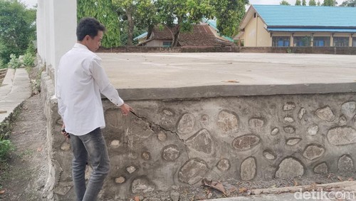 Warga menunjukkan kondisi bangunan proyek penataan lapangan olahraga Pokir DPRD Kota Bima yang sudah retak, Senin, (27/10/2025).