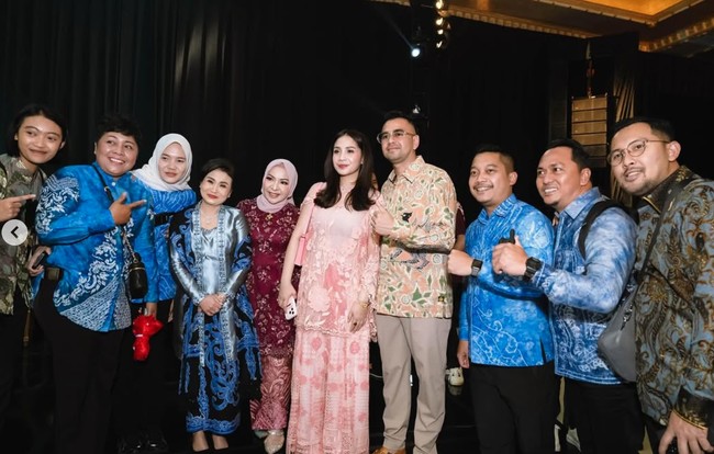 Nagita tampil simpel dengan setelan dress warna pink. Atasannya dilengkapi dengan luaran menerawang dengan detail bunga yang memberikan kesan feminin pada tampilannya. Ia kemudian memadukannya dengan celana senada bermotif yang berpotongan lebar. Foto: Instagram/@raffinagita1717