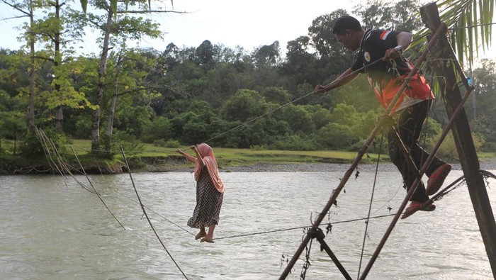 Potret Warga Bertaruh Nyawa Seberangi Sungai Lewat Jembatan Tali Sejumlah warga melintasi jembatan tali yang terbuat dari kabel listrik penghubung Desa Canggai dengan Desa Keutambang Kecamatan Pante Ceureumen, Aceh Barat, Aceh, Selasa (28/10/2025). Sebagian warga di kawasan itu masih menggunakan jembatan tali sebagai sarana penyeberangan untuk mempersingkat jarak tempuh ke desa tetangga menjadi sekitar 700 meter dari pada menggunakan jalur alternatif dan harus memutar sekitar 2,5 km hingga 4 km. ANTARA FOTO/Syifa Yulinnas/foc.