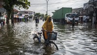 Warga berusaha melintasi jalan yang tergenang banjir setinggi lutut. Menurut data sementara BPBD Kota Semarang sebanyak 39.405 jiwa dari 29.772 KK di 18 wilayah terdampak banjir. Foto: ANTARA FOTO/Aprillio Akbar