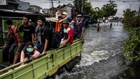 Sejumlah warga menumpang truk untuk dapat menembus banjir yang menggenangi jalur utama pantura Semarang-Surabaya di Jalan Kaligawe Raya. Foto: ANTARA FOTO/Aprillio Akbar