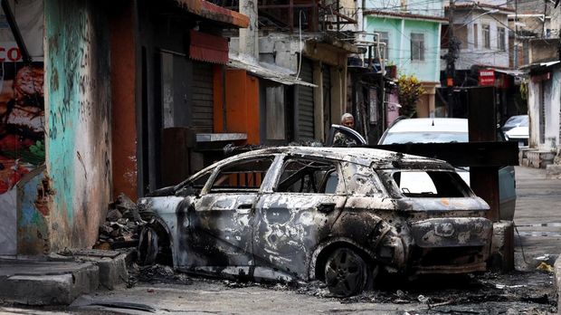 BRAZIL-VIOLENCE/ A person looks on behind a burnt car during a police operation against drug trafficking at the favela do Penha, in Rio de Janeiro, Brazil October 28, 2025. REUTERS/Aline Massuca        TPX IMAGES OF THE DAY