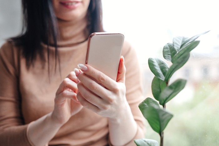 Close up young woman looking at smartphone for video online chat with friends or surf the internet or playing mobile application in relax time