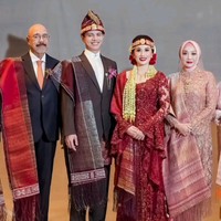 Mempelai pria Moshe Panjaitan memakai setelah jas yang dipadukan kemeja kerah tinggi. Putra tunggal dari pengusaha Mahatma Ilham Panjaitan ini memakai Ulos Ragitohang yang disampirkan di bahu kanan. Foto: Instagram/@merdisihombingluxury @myrnamyura