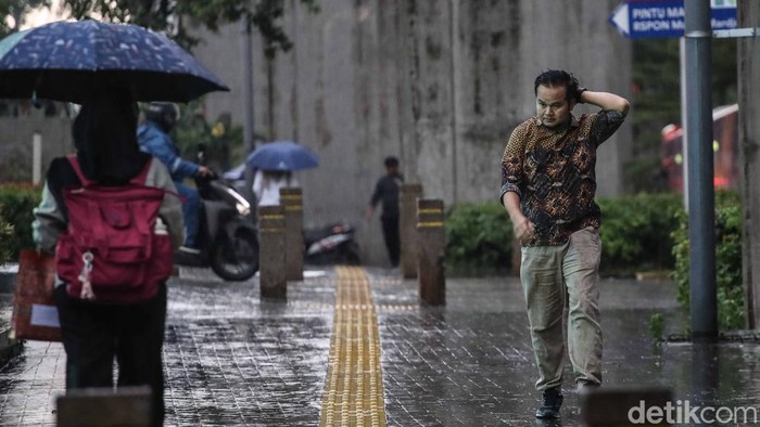 Sejumlah warga menerobos hujan di kawasan Cawang, Jakarta Timur, Kamis (30/10/2025). Ancaman mikroplastik turun bersama tetesan air hujan di Jakarta. Fenomena ini jadi alarm serius bagi lingkungan perkotaan dan warga diimbau pakai masker.