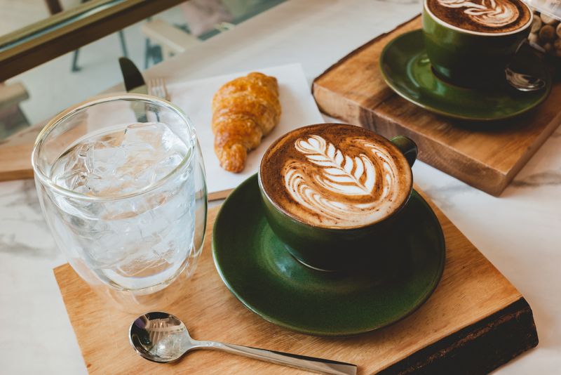 Ilustrasi cafe atau kafe Hot coffee cappuccino latte art serve with croissant in morning worm lighting.