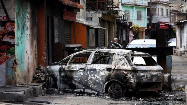 Kendaraan terbakar imbas pertempuran antara polisi Brasil dan geng narkoba berbahaya di Rio de Janeiro A person looks on behind a burnt car during a police operation against drug trafficking at the favela do Penha, in Rio de Janeiro, Brazil, October 28. REUTERS/Aline Massuca Purchase Licensing Rights