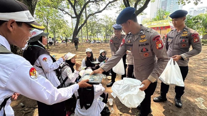 Personel Brimob Polda Metro Jaya membagikan makanan ke massa aksi guru honorer saat demonstrasi. (Dok istimewa). Personel Brimob Polda Metro Jaya membagikan makanan ke massa aksi guru honorer saat demonstrasi. (Dok istimewa).