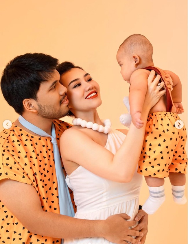 Aaliyah, Thariq, dan baby Arash tampil serasi mengenakan kostum bernuansa oranye dengan motif segitiga hitam khas Fred dan Pebbles Flintstone. Ketiganya tampil kompak memamerkan keceriaan dan keharmonisan keluarga mereka. Foto: Instagram/@thariqhalilintar