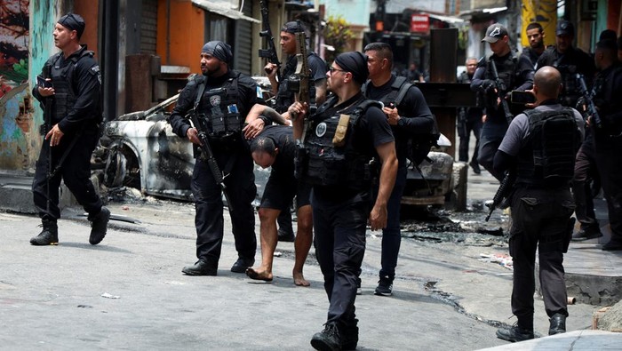 Bingkai Sepekan: Razia Narkoba Berdarah yang Tewaskan Ratusan Orang A man is detained by police officers during a police operation against drug trafficking at the favela do Penha, in Rio de Janeiro, Brazil October 28, 2025. REUTERS/Aline Massuca