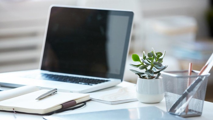 Close-up of laptop with blank screen with note pad and documents on the table at modern office