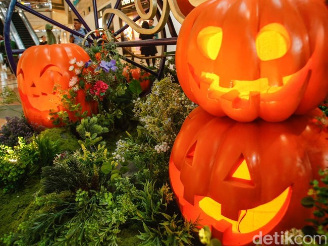 Pengunjung berfoto di depan kereta labu raksasa yang terpajang di Senayan Plaza, Jakarta, Jumat (31/10/2025).