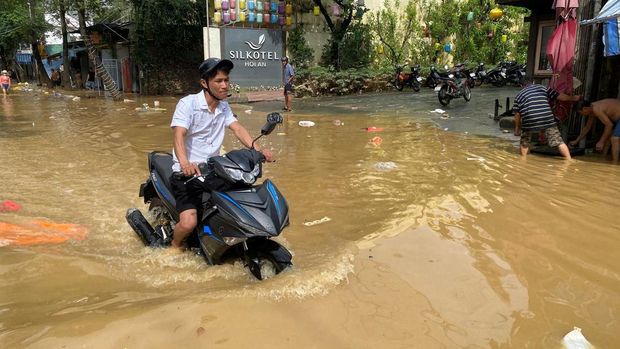 Seorang pengendara berjalan melewati jalan yang banjir di Hoi An, menyusul banjir mematikan di Vietnam tengah, 31 Oktober 2025. (REUTERS/Thinh Nguyen)