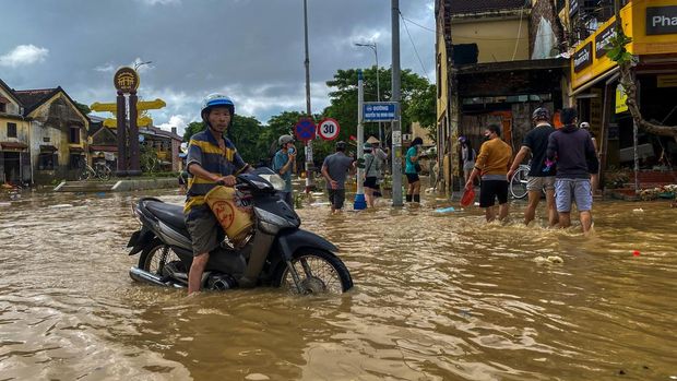 ASIA-WEATHER/VIETNAM People wade through a flooded street, as a motorist looks on, in Hoi An, following deadly floods in central Vietnam, October 31, 2025. REUTERS/Thinh Nguyen