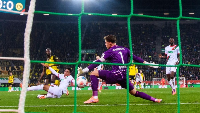 31 October 2025, Bavaria, Augsburg: Soccer: Bundesliga, FC Augsburg - Borussia Dortmund, Matchday 9, WWK-Arena. Serhou Guirassy (l, Borussia Dortmund) scores the goal to make it 0:1 against Noahkai Banks (FC Augsburg) and goalkeeper Finn Dahmen (r, FC Augsburg). Photo: Tom Weller/dpa - IMPORTANT NOTE: In accordance with the regulations of the DFL German Football League and the DFB German Football Association, it is prohibited to utilize or have utilized photographs taken in the stadium and/or of the match in the form of sequential images and/or video-like photo series. (Photo by Tom Weller/picture alliance via Getty Images)