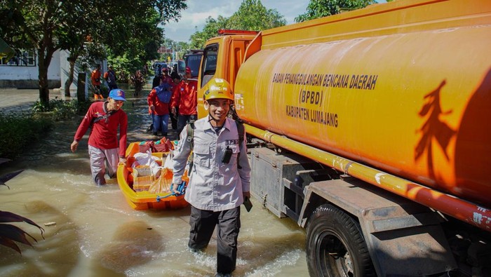 Petugas BPBD saat menyalurkan bantuan makanan di Rowokangkung, Lumajang, Jawa Timur, Sabtu (1/11/2025). Pemkab Lumajang memberikan bantuan air bersih dan makanan siap saji untuk korban banjir serta melakukan normalisasi sejumlah sungai karena luapan airnya telah menyebabkan 895 rumah warga tergenang banjir di wilayah tersebut. ANTARA FOTO/Irfan Sumanjaya/tom.